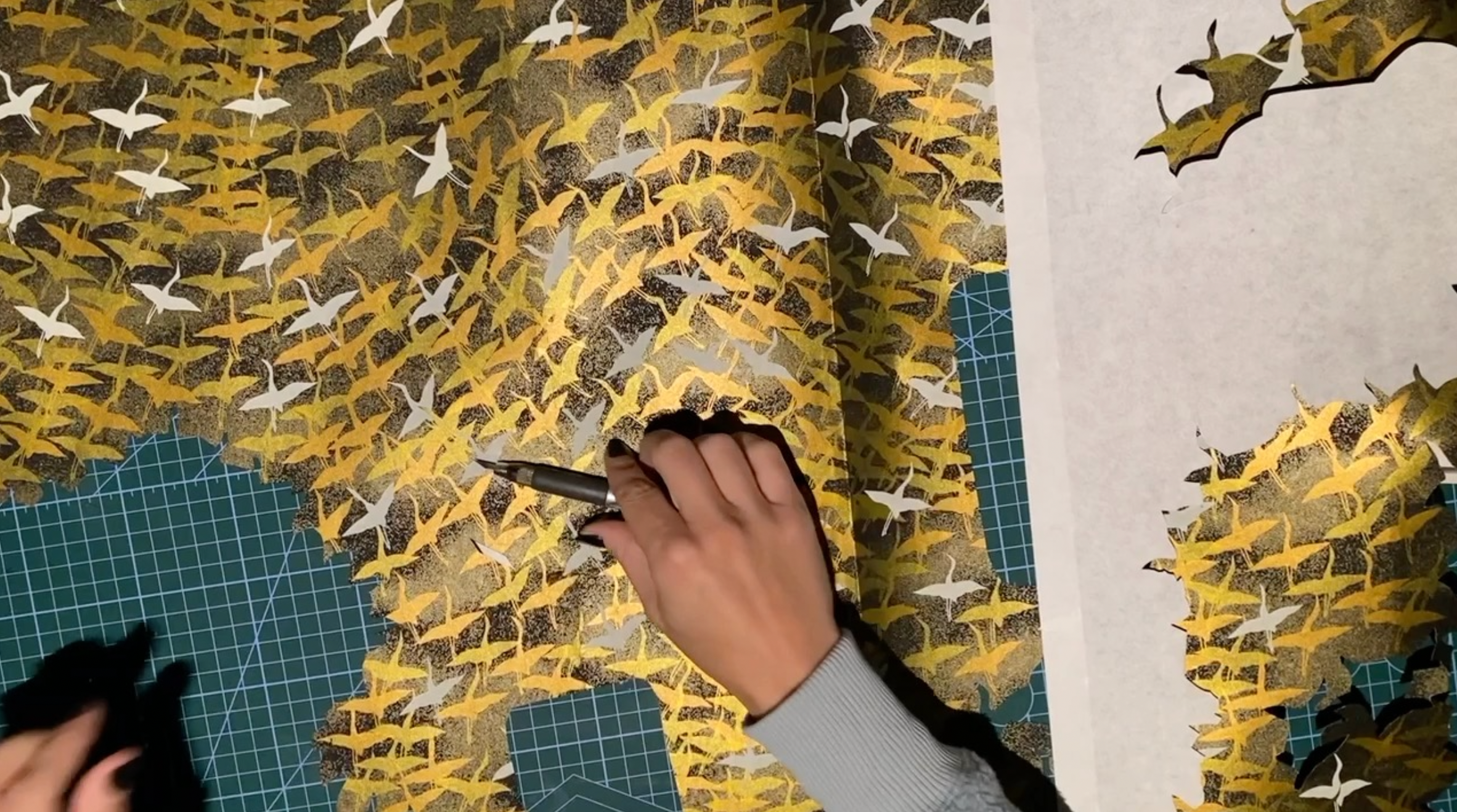 Load video: A close-up time-lapse of the artist cutting chiyogami paper with a paper knife.